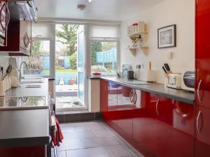 a kitchen with red cabinets and a large window at Chapel Street Cottage in Amlwch