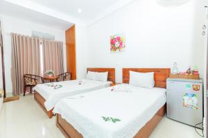 a bedroom with two beds and a refrigerator in it at Khách sạn Ciao Quy Nhơn in Quy Nhon