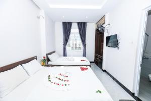 a white bedroom with two beds and a window at Khách sạn Ciao Quy Nhơn in Quy Nhon
