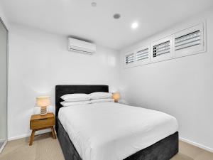 una camera bianca con un letto e due finestre di Modern 1-Bedroom Apt with Sweeping Water Views a Batemans Bay