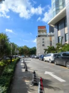 un estacionamiento con autos estacionados frente a un edificio en Newyantai Hotel Hainan, en Haikou