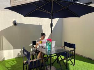 une femme assise à une table sous un parapluie dans l'établissement Alfonsina Hostel, à Buenos Aires