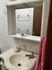um lavatório de casa de banho com espelho e toalhas cor-de-rosa em Apto duplex, frente ao mar. em São Vicente