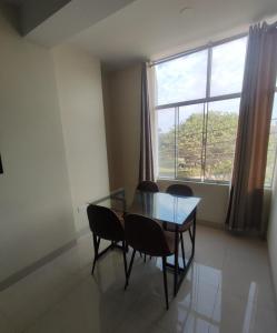 a dining room with a glass table and chairs and a window at Soto Apartamentos in Chiclayo