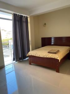 - une chambre avec un lit et une grande fenêtre dans l'établissement Soto Apartamentos, à Chiclayo