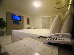 a bedroom with a bed with a phone on a table at Hotel na Beira Mar de Fortaleza - Vista Mar in Fortaleza