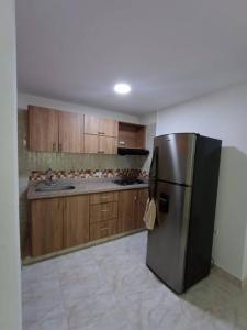 eine Küche mit einem Kühlschrank aus Edelstahl und Holzschränken in der Unterkunft Agradable y Económico Apartamento in Santa Fe de Antioquia