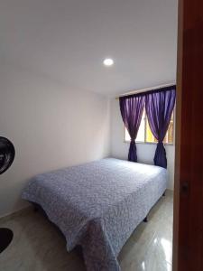 Schlafzimmer mit einem Bett mit lila Vorhängen und einem Fenster in der Unterkunft Agradable y Económico Apartamento in Santa Fe de Antioquia
