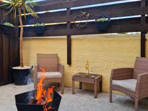 a fire pit with two chairs and a table with wine glasses at The Barn Annexe in St. Just