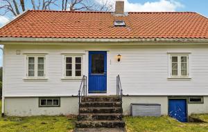 Biały dom z pomarańczowym dachem i niebieskimi drzwiami w obiekcie 3 Bedroom Cozy Home In Farsund w mieście Farsund