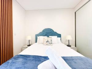 une chambre avec un grand lit et une tête de lit bleue dans l'établissement City Living Made Easy : 1 Bed Apt in Ashfield Heart, à Sydney