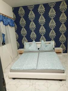 1 dormitorio con 1 cama con pared azul en Château angele w&b, en Lomé
