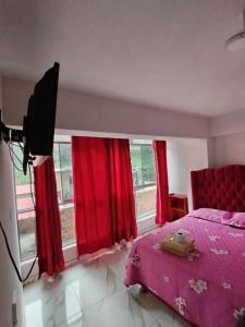 sypialnia z różowym łóżkiem i czerwonymi zasłonami w obiekcie Mi Sr. Cautivo w mieście Churin