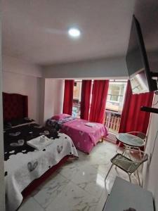 sypialnia z 2 łóżkami i oknem z czerwonymi zasłonami w obiekcie Mi Sr. Cautivo w mieście Churin