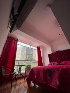 sypialnia z czerwonym łóżkiem i dużym oknem w obiekcie Mi Sr. Cautivo w mieście Churin