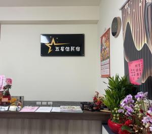 a reception desk with a sign on the wall at 五星佶民宿 in Jinning