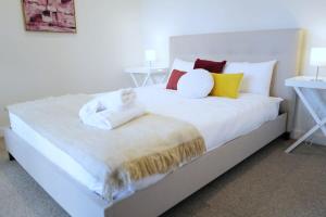 una gran cama blanca con almohadas coloridas. en Lovely Home in midtown Box Hill with two bedrooms, en Box Hill