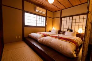 a large bed in a room with two windows at Kigannoyado Aoshima Jizoan in Miyazaki