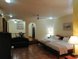 1 dormitorio con 2 camas, silla y sofá en Apartotel Don Francisco, en San José