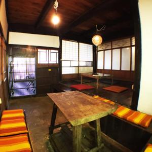 una camera con tavolo e panche in un edificio di 古民家一棟貸しNano Village Okayama a Kaga