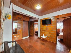 uma sala de estar com televisão numa parede de tijolos em Hotel Finca Recreacional La Fortaleza 