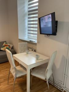 una mesa y sillas blancas con TV en la pared en Apartment na Zamkowej, en Cracovia