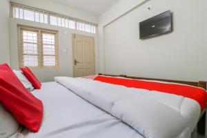 sypialnia z łóżkiem z czerwonymi poduszkami i telewizorem w obiekcie Appas Residency w mieście Ambalavayal