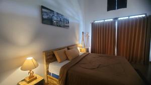 a bedroom with a bed and a lamp and a window at Batur Volcano Basecamp in Kubupenlokan