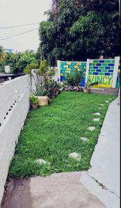 a grassy yard next to a wall and a sidewalk at Spacious Home away from Home! 1 Bedroom in Kingstown