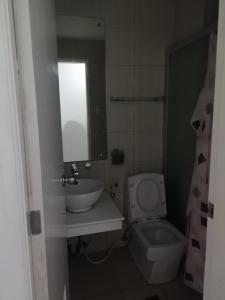 a bathroom with a sink and a toilet and a mirror at Birchtower studio in Manila
