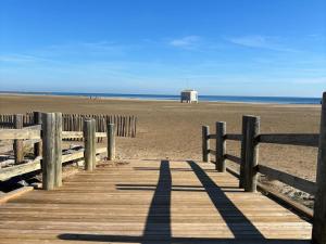 een houten promenade die leidt naar een strand met een schuur bij Chalet Gruissan, 5 pièces, 7 personnes - FR-1-784-2 in Gruissan