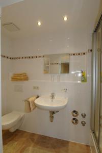 ein weißes Bad mit einem Waschbecken und einem WC in der Unterkunft Ferienwohnungen im Alpengästehaus Marzoll - Bad Reichenhall in Bad Reichenhall