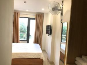 een slaapkamer met een bed en een raam met een ventilator bij KHÁCH SẠN GIA HÒA 3 in Vung Tau