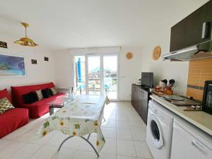 cocina y sala de estar con sofá rojo en Appartement Marseillan-Plage, 2 pièces, 6 personnes - FR-1-326-816, en Marseillan