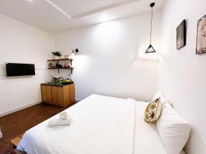 a white bedroom with a bed and a tv at Maison Bùi Viện in Ho Chi Minh City