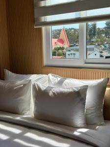łóżko z białymi poduszkami przed oknem w obiekcie HOANG LINH PHAT HOTEL w mieście Da Lat