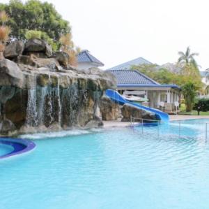 eine Wasserrutsche in einem Pool mit Wasserfall in der Unterkunft Bertam Villa Suites - Golf Resort by RZAC in Kepala Batas