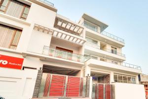 a white building with red shutters on it at Collection O Pratik Inn in Chinhat