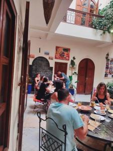 un grupo de personas sentadas en una mesa comiendo en Riad white flowers en Marrakech