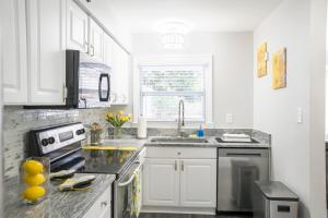 a white kitchen with a sink and a stove at Cozy home, 10 minutes away from downtown in Charlotte