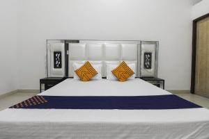 a bedroom with a large bed with orange and blue pillows at SPOT ON Green Valley in Meerut