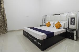 a bedroom with a large bed with yellow and blue pillows at SPOT ON Green Valley in Meerut