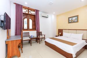 Schlafzimmer mit einem Bett, einem Schreibtisch und einem TV in der Unterkunft Paradis Hotel Quy Nhon in Quy Nhon