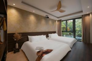 2 camas blancas en una habitación con ventana en Brilliant Nature Suites & Spa, en Hanói