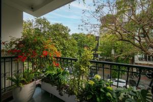a balcony with plants and red flowers on it at Brilliant Nature Suites & Spa in Hanoi