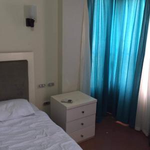 um quarto com uma cama e uma cómoda e cortinas azuis em شقه مصيفيه شاطى الفردوس البيطاش em Alexandria