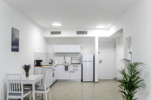 eine Küche mit weißen Geräten sowie einem Tisch und Stühlen in der Unterkunft Luxury Suite Apartment #60 By Hashdera Eilat in Eilat