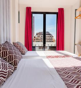 1 dormitorio con 1 cama con cortinas rojas y ventana en Hostal Juliette-Gran Vía, en Madrid