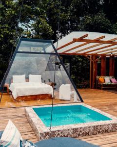 a swimming pool with a bed and a glass house at Macas Glamping in Macas