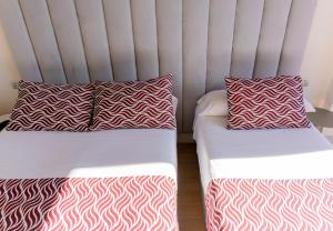 two beds with red and white pillows in a room at Hostal Juliette-Gran Vía in Madrid